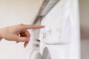 Hand inspecting the side panel of a washing machine, illustrating a leak diagnosis