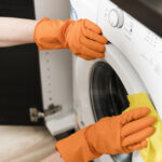 Person cleaning the door gasket of a front-load washing machine