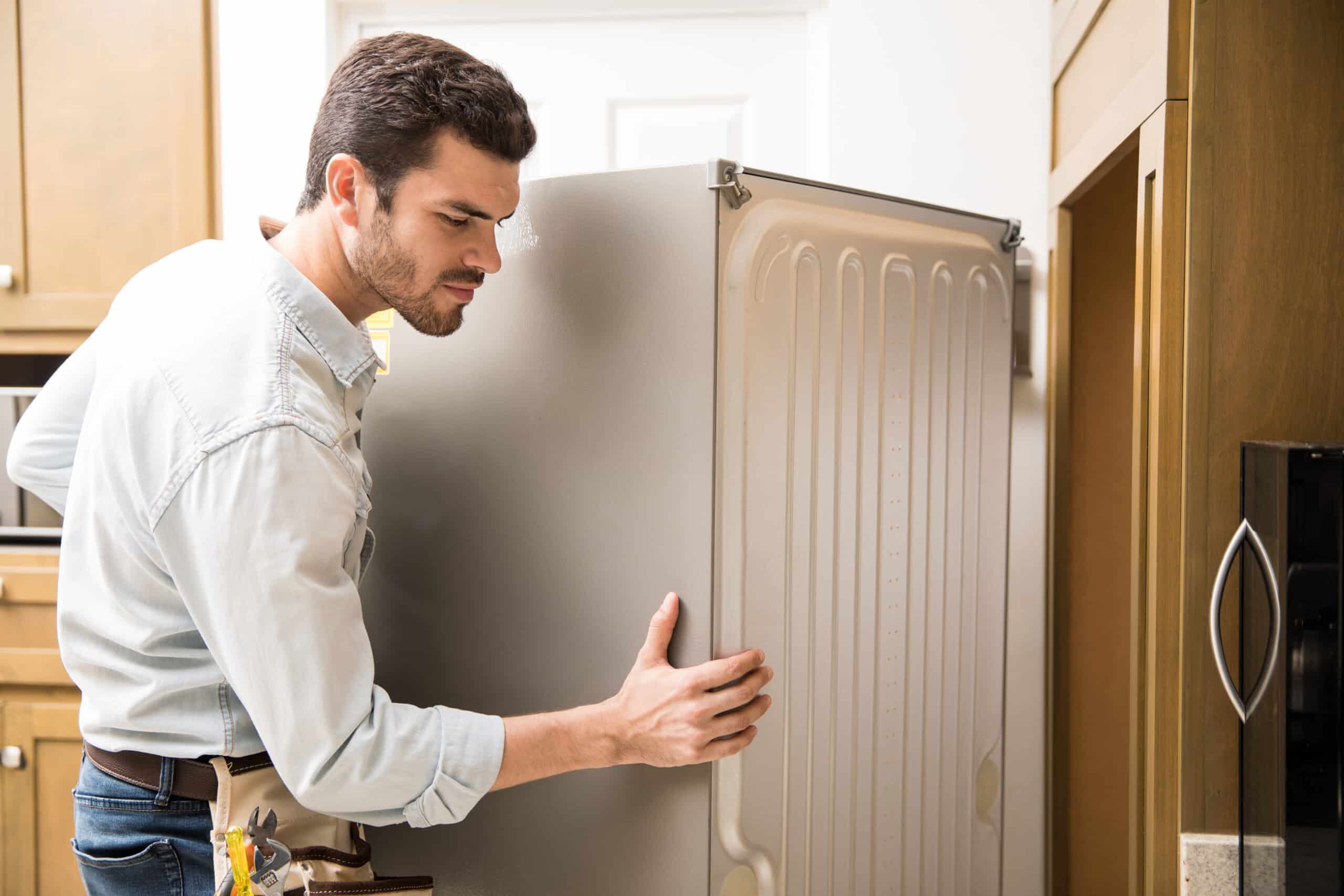 Technician exposing the back panel of a refrigerator to check for cooling problems