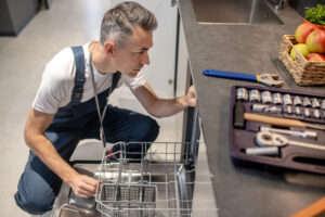 Technician diagnosing an open dishwasher during a repair inspection