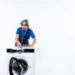 Repairman with a head lamp using a stethoscope on a washing machine, illustrating Whirlpool washer error code F22 motor communication error