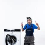 Repairman holding a stethoscope sitting near a washing machine, illustrating Whirlpool washer F15 error code drum position sensor fault