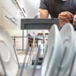 Man loading a detergent tablet into a dishwasher