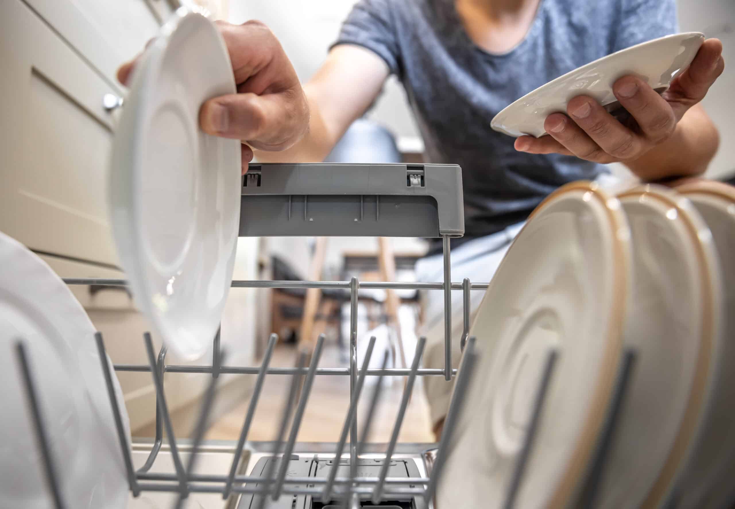 Man taking dishes out of an open dishwasher, illustrating Whirlpool dishwasher error code F9E1 long drain