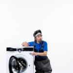 Repairman sitting near a washing machine, illustrating Whirlpool washer F09 error code water level fault