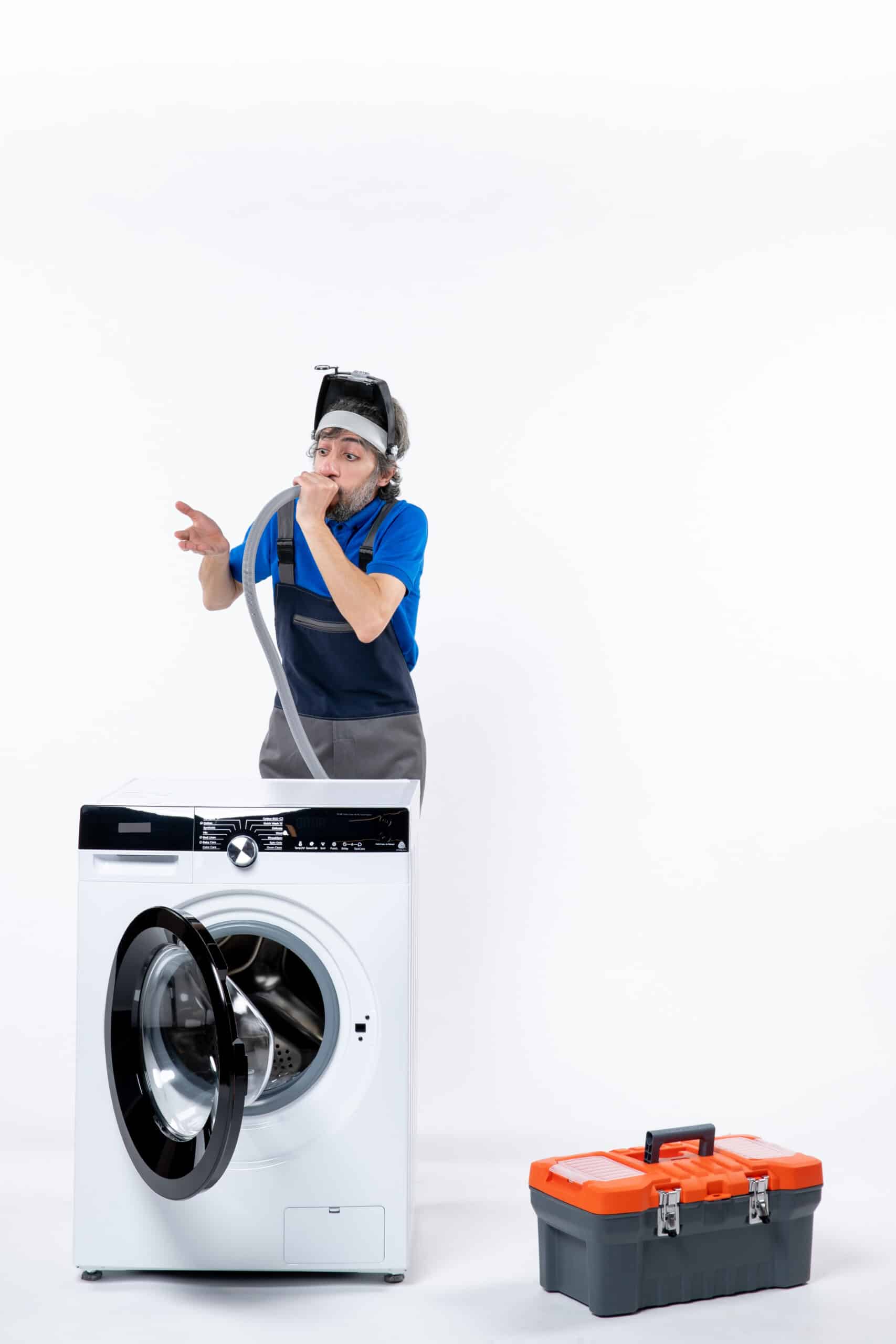 Confused repairman in uniform standing behind a washing machine, illustrating Whirlpool washer Sud error too many suds