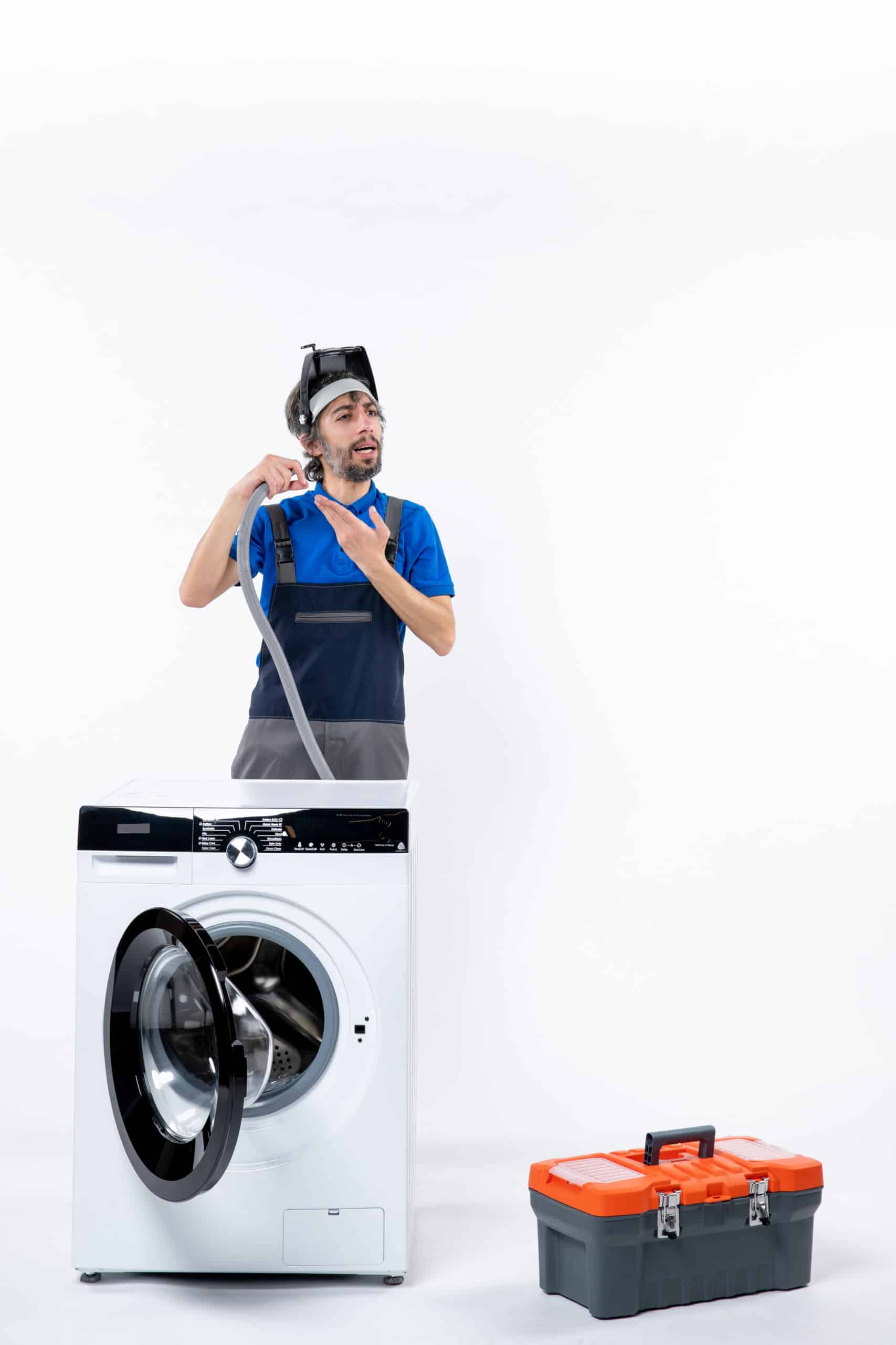 Confused repairman in uniform holding a plastic pipe behind a washing machine, illustrating Whirlpool washer F13 error code dispenser fault