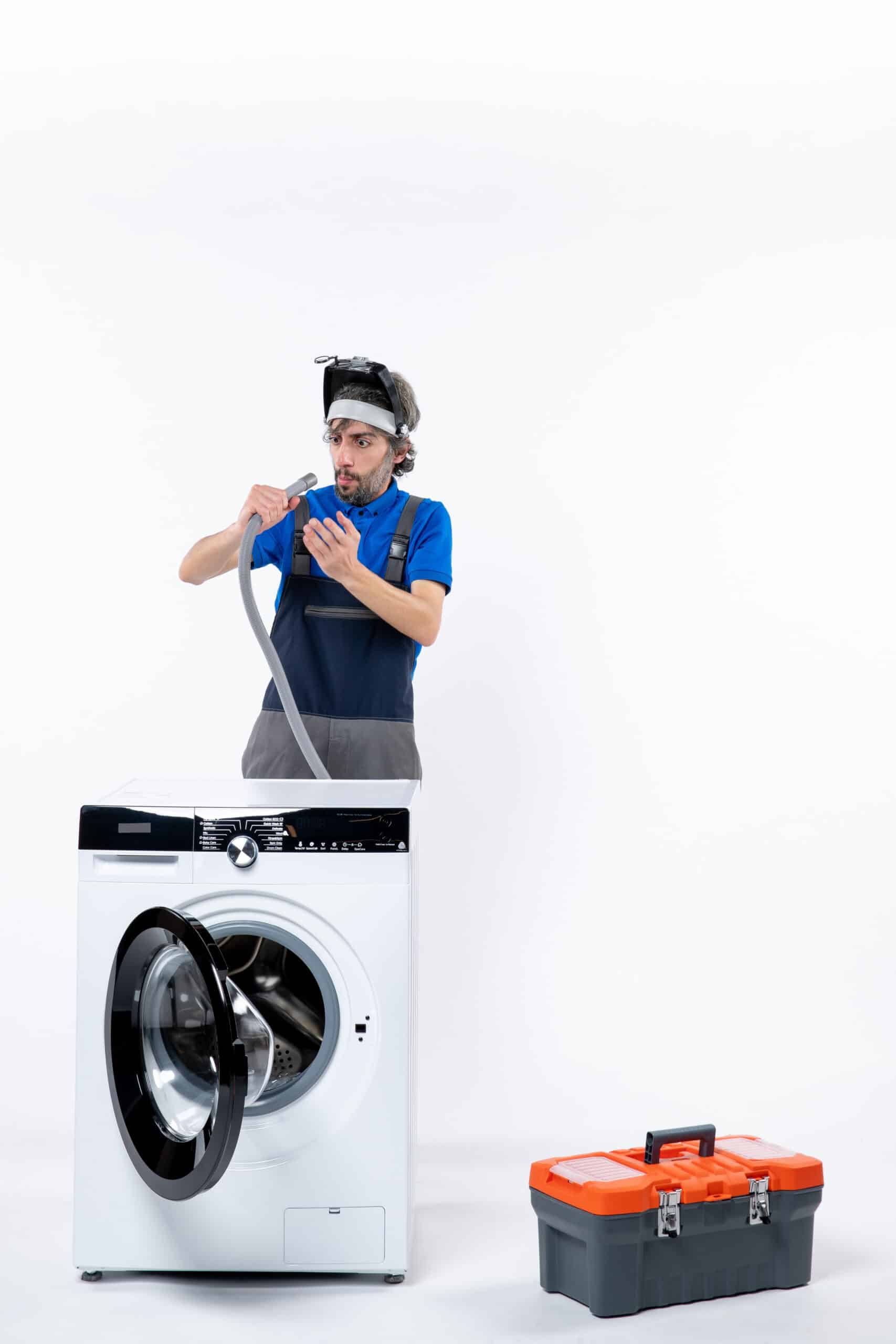 Repairman in uniform checking a pipe behind a washing machine, illustrating Whirlpool washer error code F09 water level error