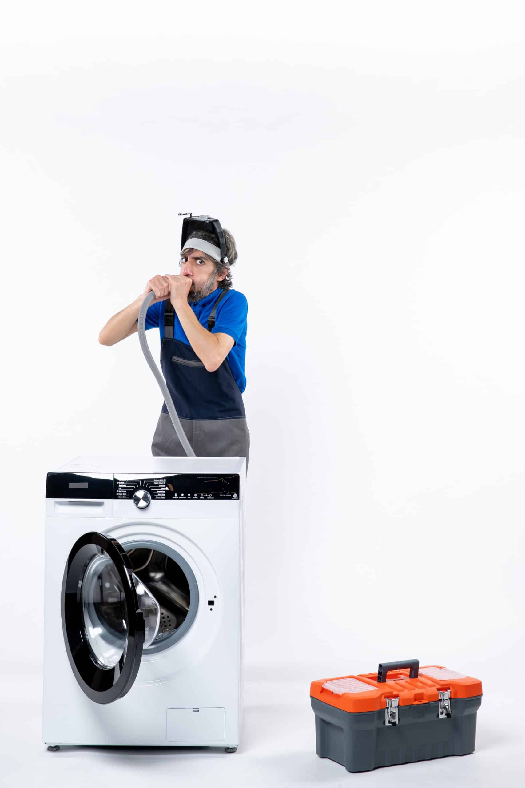 Young repairman in uniform standing behind a washing machine clearing a pipe, illustrating LG washer error code FE overfill fault