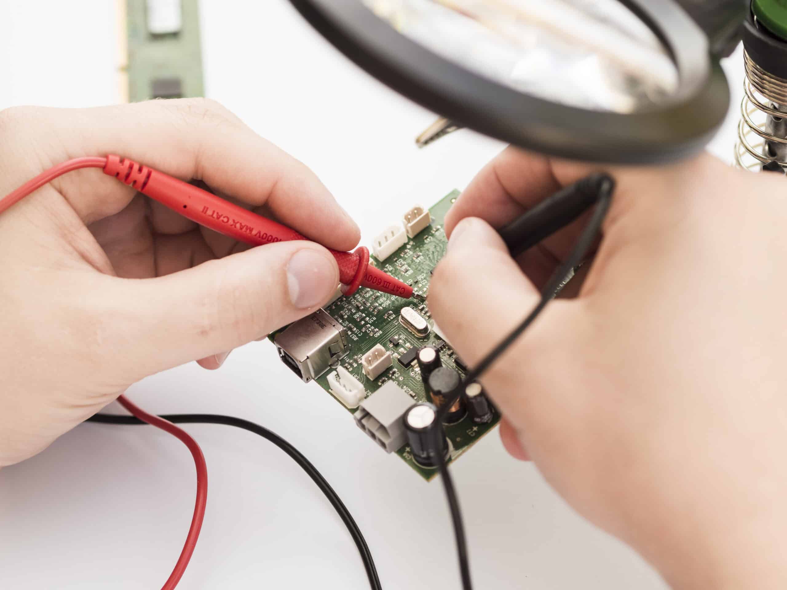 Technician using a multimeter to check a circuit board, illustrating LG dryer error code AE communication fault