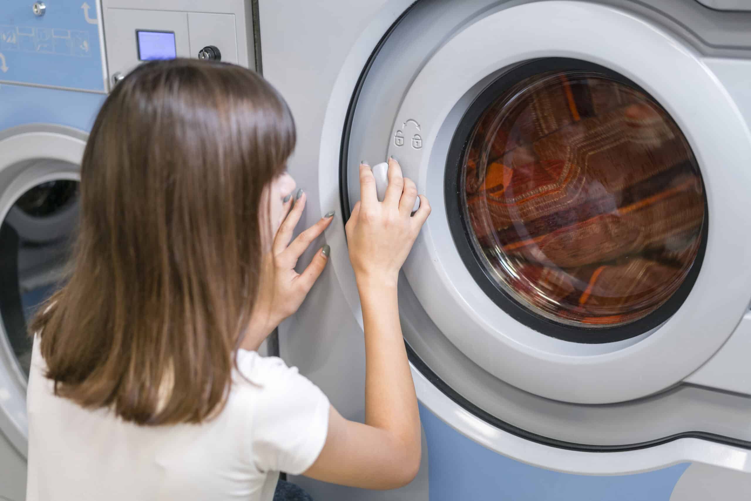 Woman closing a washing machine door before starting a wash cycle