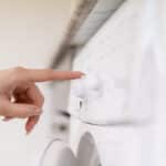 Hand touching a washing machine control panel