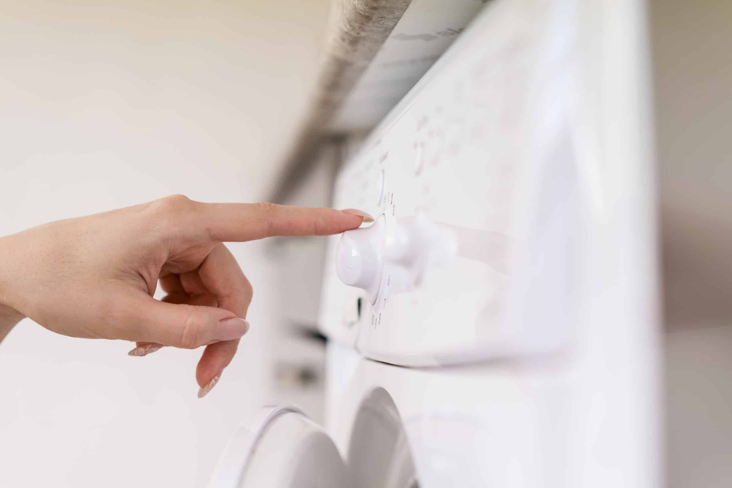 Hand touching a washing machine control panel