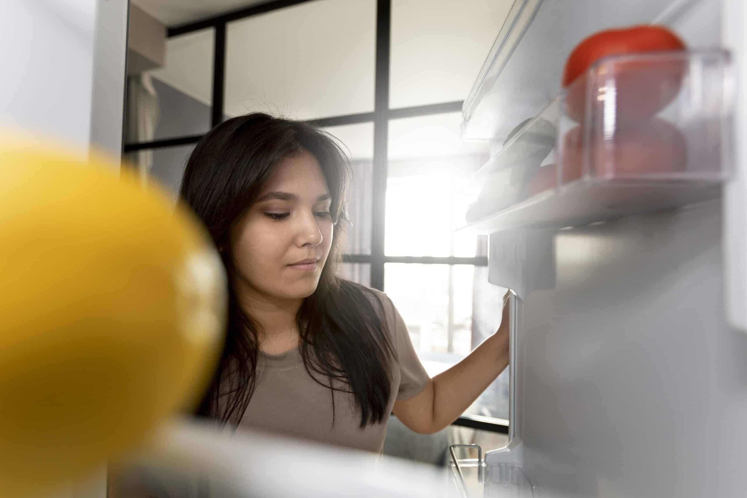Person checking the interior compartment of a refrigerator, illustrating Samsung refrigerator error code 22E fridge fan fault