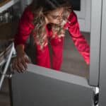 Woman checking refrigerator food at night after a Whirlpool refrigerator power outage error PO