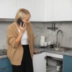 Woman calling a technician about a kitchen appliance problem, illustrating Whirlpool dishwasher error code F4 drain fault