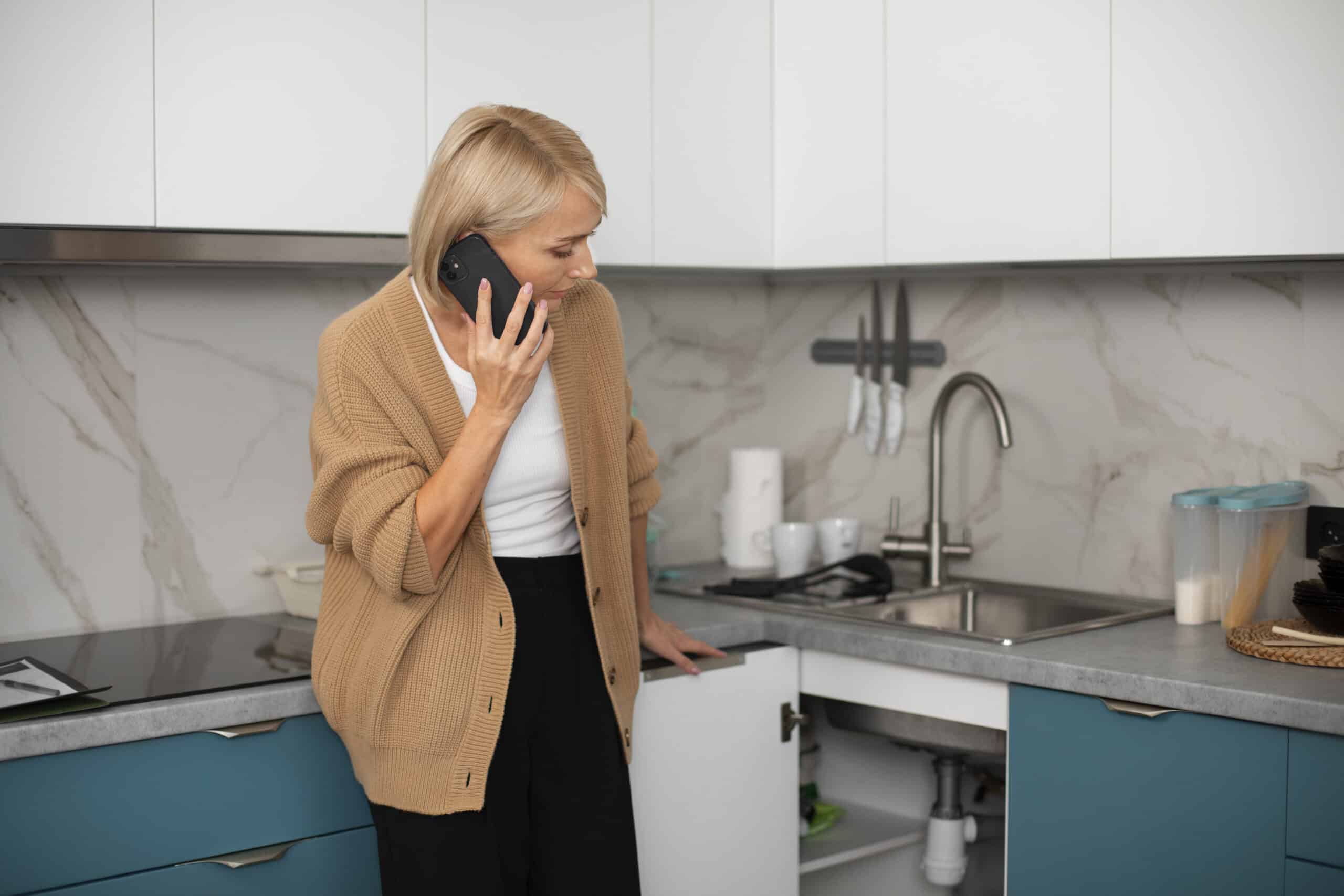 Woman calling a technician about a kitchen appliance problem, illustrating Whirlpool dishwasher error code F4 drain fault