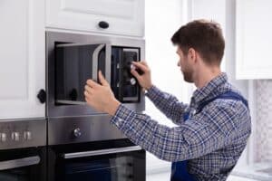 Technician repairing a microwave oven, checking internal components