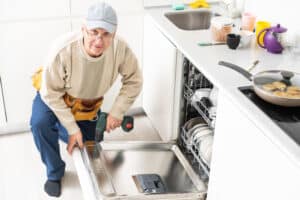 Technician repairing a Whirlpool dishwasher that is not draining