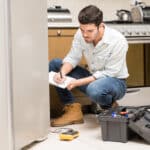 Technician filling out a repair report next to a refrigerator, illustrating LG refrigerator FF freezer fan error