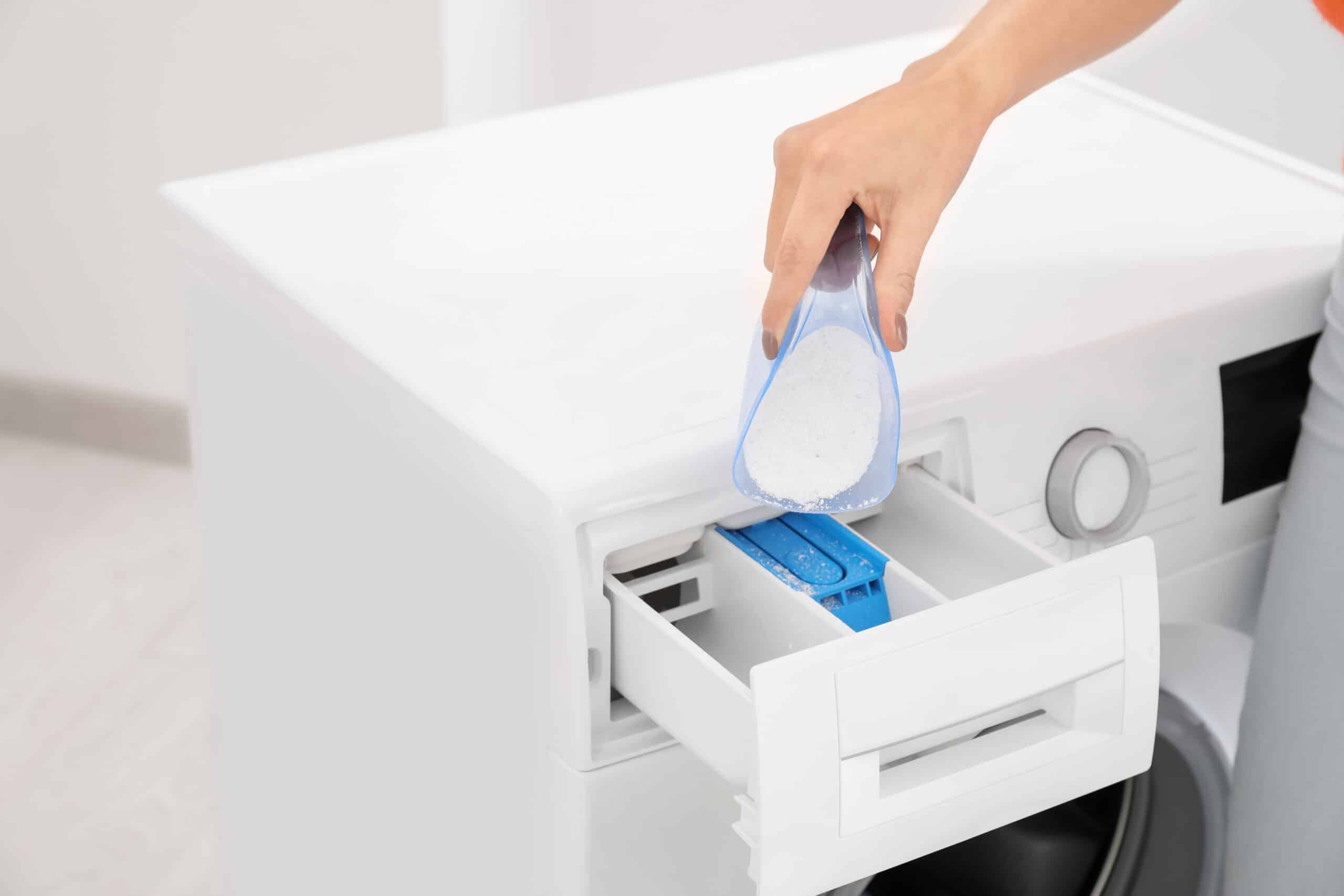 Person filling the detergent dispenser drawer of a Samsung washing machine, related to SUD excess suds error