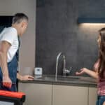 Water leak being pointed out to a repair technician with a tool case, illustrating Samsung dishwasher error code LE leakage error