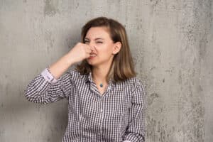 Woman covering her nose because of a bad smell coming from the garbage disposal