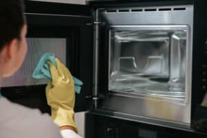 Woman cleaning an oven, relevant to a locked oven door after a self-clean cycle
