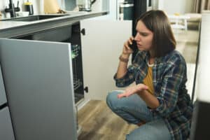 Woman calling for help to repair a dishwasher that is not draining