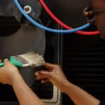 Technician cleaning a blocked ventilation fan, illustrating GE dryer error code d80 restricted airflow