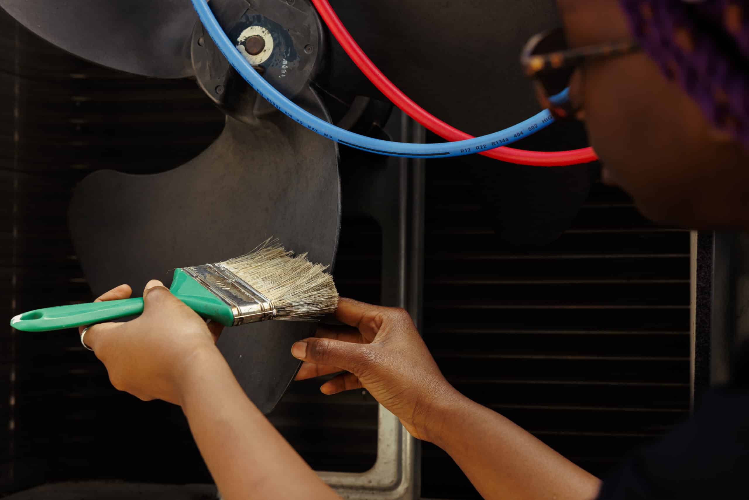 Technician cleaning a blocked ventilation fan, illustrating GE dryer error code d80 restricted airflow