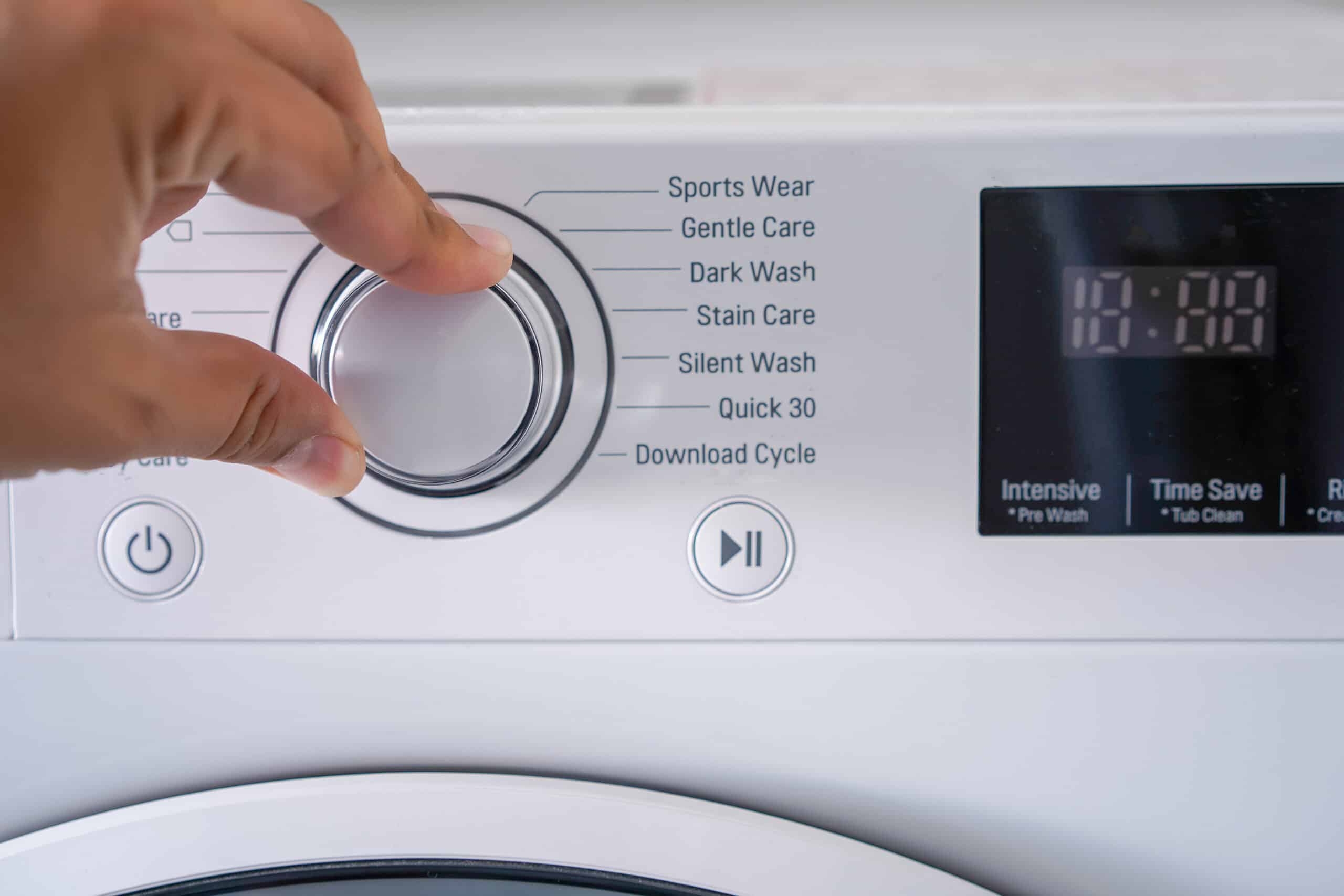 Hand adjusting the control knob of a washing machine