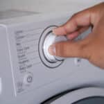 Hand adjusting the control knob of a washing machine