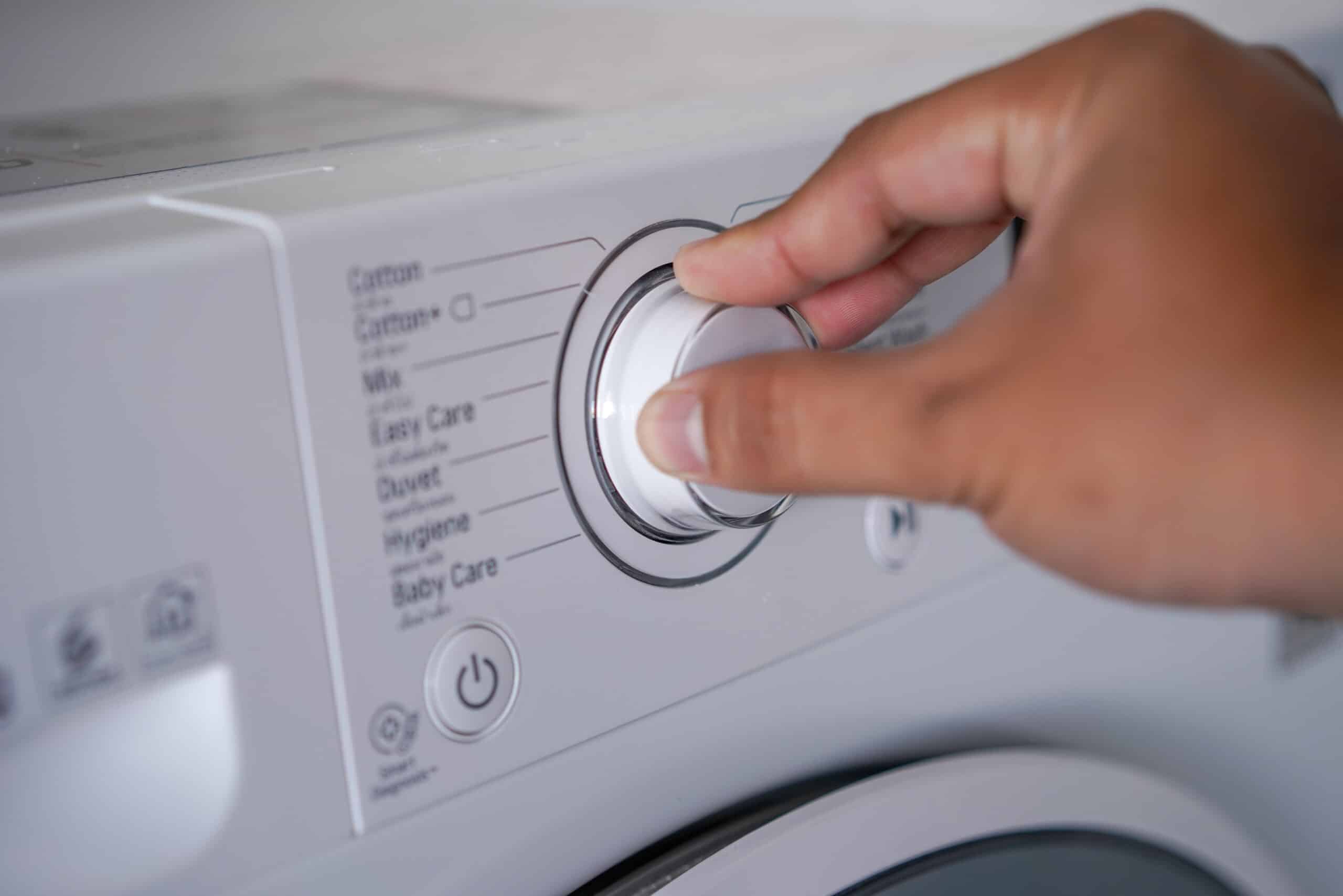 Hand adjusting the control knob of a washing machine