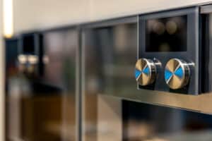 Built-in oven with two metal control knobs and a dark display panel in a modern kitchen